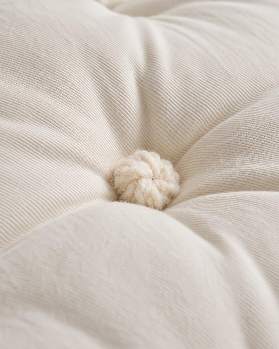 Cream cotton twill with a hand-tied wool rosette